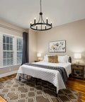 Bedroom with Six Light Wagon Wheel Chandelier In Black Industrial Farmhouse Style over bed, rustic decor accents visible