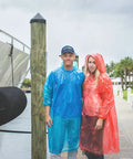 Couple wearing extra thick family rain ponchos 8 pack for men women teens and kids disposable emergency rain gear with drawstrings durable waterproof ponchos for travel and Disney trips stay dry on the go.