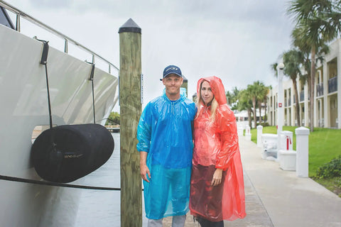 Couple wearing extra thick family rain ponchos 8 pack for men women teens and kids disposable emergency rain gear with drawstrings durable waterproof ponchos for travel and Disney trips stay dry on the go.