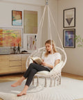 Person reading in a Boho Macrame Hammock Chair Swing With Overstuffed Cushion For Indoor And Outdoor Cozy Vibes Beige Solid Steel Frame Easy Setup Hanging Chair For Balcony Porch Bedroom.