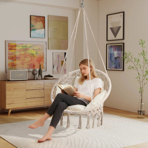 Person reading in a Boho Macrame Hammock Chair Swing With Overstuffed Cushion For Indoor And Outdoor Cozy Vibes Beige Solid Steel Frame Easy Setup Hanging Chair For Balcony Porch Bedroom.