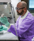 Lab worker in Purple Medium Disposable Lab Jackets Crafted In Lightweight SMS 50 GSM 30 Inch Hip Length With Snap Front Knit Cuffs