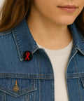 Woman wearing a denim jacket with a red ribbon lapel pin, symbolizing support for a cause, attached to the collar.