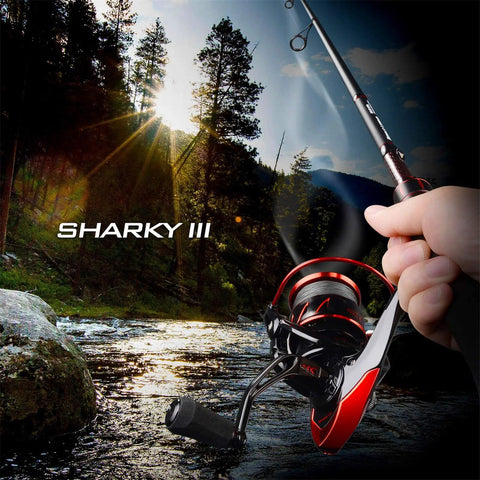 Angler holding Sharky III 3000 Spinning Fishing Reel for Saltwater and Freshwater over scenic river at sunset, showing graphite build