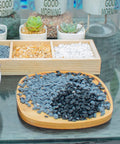 18lb Black Cactus Pea Gravel Rocks 1 Quarter Inch Pebbles for Indoor Plants and Succulents arranged on a wooden tray