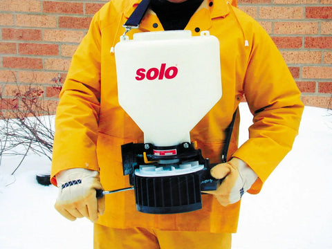 20 Pound Capacity Portable Chest Mount Spreader With Cross Shoulder Strap in use by person in orange suit outdoors