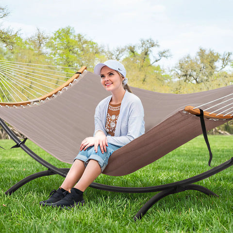 A woman sitting on a Sturdy Standing Hammock With Foldable Steel Stand For Patio Or Deck, Portable 2-3 Person Hammock That Holds Up To 475 Lb