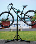 Bike Repair Stand With 360 Degree Rotating Clamp Holds Up To 110 Lbs Adjustable Jaws 1 To 1.5 Inches, holding mountain bike outdoors