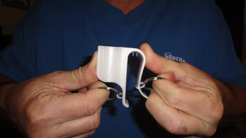 Person holding Mighty Putter Clip Holder for Golf Bag with Dual Ring Mounts, showing durable nylon clip and installation rings.