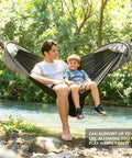 Father and son relaxing in All In One Camping Hammock With Mosquito Net And Rain Fly Tarp by a river