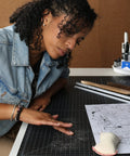 Artist using Pro Drafting Dry Cleaning Pad 3 Oz for Art Graphite and Pastels wipes away smudges from drawing board.