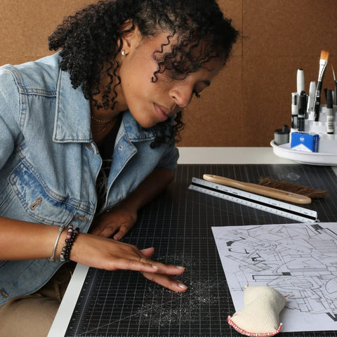 Artist using Pro Drafting Dry Cleaning Pad 3 Oz for Art Graphite and Pastels wipes away smudges from drawing board.