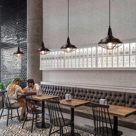Black Pendant Light Set 3 Pack, Industrial Farmhouse Pendant Lighting over rustic dining tables in a modern cafe setting, vintage style.