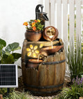 Solar Powered Rustic Barrel Water Fountain With LED Lights, 29 Inch Tall 4 Tier Cascading Outdoor Waterfall in a garden setting.