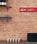 Official Kansas City Chiefs NFL Aluminum Metal Street Sign 4X15 Inch Durable Weatherproof All Indoor And Outdoor Wall Art Decor For Man Cave displayed on a brick wall.