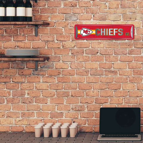 Official Kansas City Chiefs NFL Aluminum Metal Street Sign 4X15 Inch Durable Weatherproof All Indoor And Outdoor Wall Art Decor For Man Cave displayed on a brick wall.