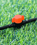 Close-up of 20 Pack One Quarter Inch Drip Irrigation Valve Fittings With In Line Shut Off Valves Barbed Connectors in grass