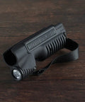 Integrated Tactical Forend Weapon Light For Mossberg Shockwave 12 Gauge With Six And Three Quarters Inch Action Slide, 1000 Lumen, 20000 Candela, Ambidextrous Controls, Strap Included, Black on wooden surface