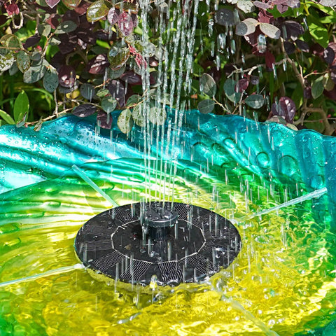 1.4W Solar Bird Bath Fountain Pump with upgraded panels, installed in a garden, spraying water into a colorful bird bath