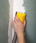Person using Lightweight Dust Free Sponge Sander Kit With Vacuum Hose And Two Sponges on a corner wall surface