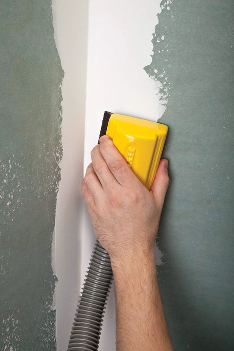 Person using Lightweight Dust Free Sponge Sander Kit With Vacuum Hose And Two Sponges on a corner wall surface