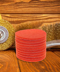 10 Pcs Orange Nylon Hook And Loop Electric Sanding Discs 2000 Grit stacked on wooden surface with tools for buffing.
