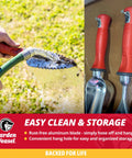 Pro Grade Multi Use Transplanter Tool cleaning serrated blade with hose next to two trowels with red handles for garden use