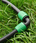 Half Inch Drip Irrigation Fittings 12 Pack Barbed 90 Degree Elbows With Locked Nuts connected to tubing in a garden setup