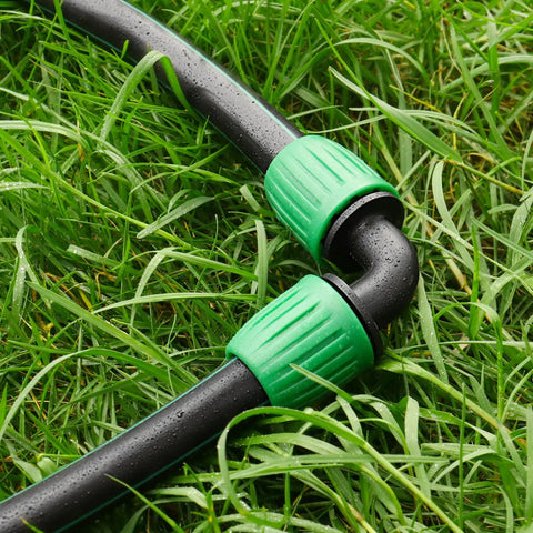 Half Inch Drip Irrigation Fittings 12 Pack Barbed 90 Degree Elbows With Locked Nuts connected to tubing in a garden setup