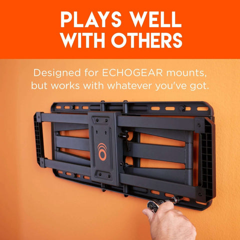 Front view of a black TV wall-mount bracket attached to an orange wall; hand tightening a lag bolt.