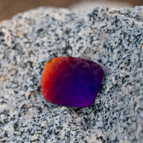 Apex Polarized PRO Replacement Lenses For Electric Stacker Sunglasses In Cool Violet Tint resting on a textured granite rock.