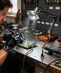 Man using Magnetic Helping Hands Soldering Tool with Four Flexible Gooseneck Clamps and Magnetic Base for PCB repair.