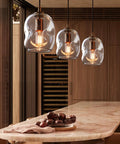 Dope Clear Art Glass Pendant Lights 2 Pack For Kitchen Island And Dining Room Table Modern Organic Globe Ceiling Fixture with Sleek Brass Gold Hardware above marble countertop.