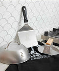 9 Inch Stainless Steel Cheese Melting Dome For Griddles And Flat Tops, Locks In Heat, shown with spatula and grill press on counter