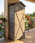 Tall Outdoor Wooden Storage Shed With Tall Vertical Tool Cabinet Folding Table And Removable Shelves For Your Patio Deck Backyard And Lawn Grey Finish 30x20x70 Inches against floral backdrop.
