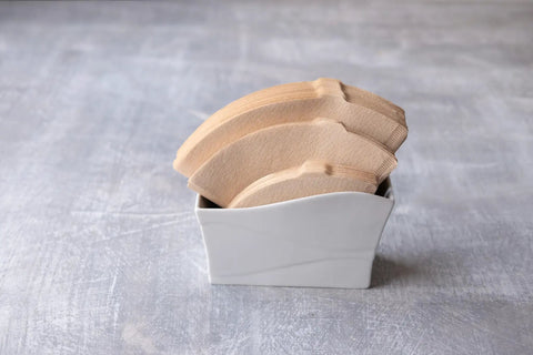 V60 Paper Coffee Filter Size 02 Natural 200 Count For Pour Over Cone Dripper Fits 1 To 4 Cups Easy To Use Made In Japan Barista Grade Natural Paper For Clean Brew And Rich Flavor in a white holder