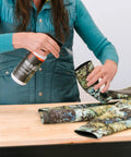 Person applying Neo Slix Wetsuit Entry Lubricant 16.9 Fl Oz Water Based Silicone Free Formula to wetsuit sleeve on table