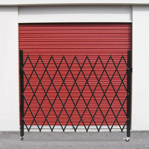 Built Like A Tank Foldable Security Gate 48 By 71 Inch Expandable Iron Frame Barrier mounted against a red garage door.