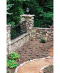 Stone wall and garden path with black iron fence and lamp post in greenery