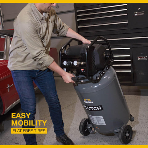 Man moving 29 Gallon Portable Air Compressor With 2.5 HP Motor, 120 Volt Power, 175 PSI Max with flat-free tires in garage