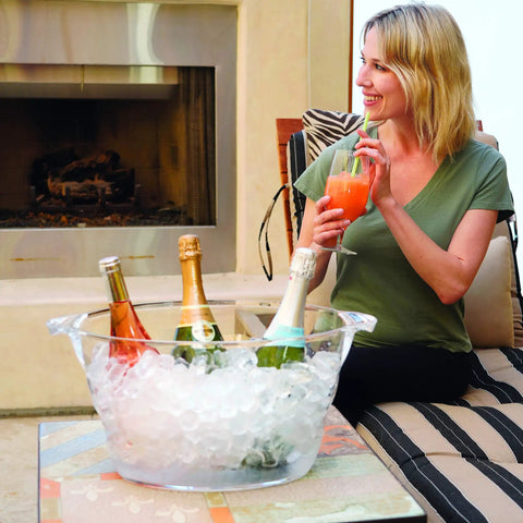 Acrylic Oval Party Tub With Handles For Chilling Drinks Indoor Outdoor Bar Use Crystal Clear Beverage Cooler Ice Tub For Wine Beer And Soda Easy Carrying Drink Station on a table with drinks and ice, woman holding a drink.