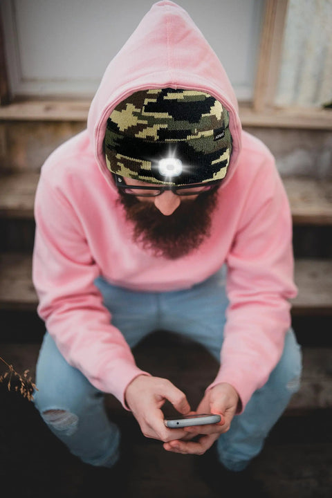 Person wearing Lighted Beanie Hat With USB Rechargeable Four LED Headlamp Bright Running Cap For Men And Women Camouflage Green Knit
