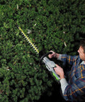 Person using Cordless Hedge Trimmer 24 Inch With Brushless Motor, Dual Action Hardened Steel Blades on dense greenery.