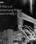Monochrome image of a Moen exhibition booth with "Moen. Faucets For A Lifetime" banner, celebrating 85 years of water experiences.