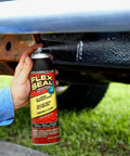 White 14 Oz Waterproof Rubber Spray On Sealant Coating That Stops Leaks Instantly Flexible After Drying Ideal For Gutters Wood RVs Campers Roofs Skylights Windows And More in use under a vehicle.