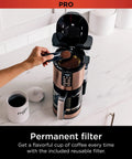 Person using Programmable XL 14 Cup Barista Grade Coffee Maker Pro with permanent filter, copper finish, on kitchen counter.