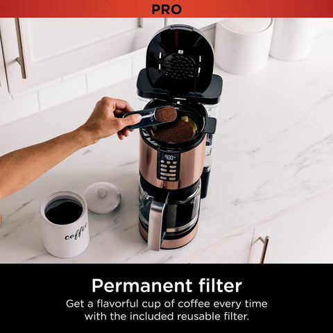 Person using Programmable XL 14 Cup Barista Grade Coffee Maker Pro with permanent filter, copper finish, on kitchen counter.