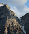 Rugged mountain peak under cloudy sky, showcasing nature's majesty and rugged terrain.