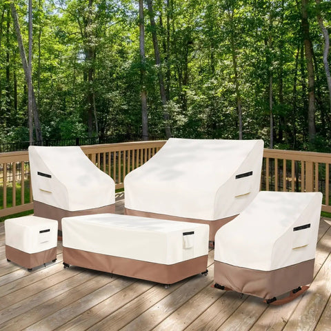 Outdoor furniture covered with beige and brown protective covers on a wooden deck, surrounded by trees.