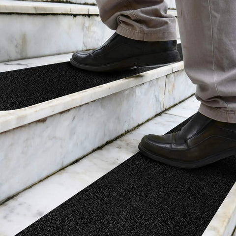 Person stepping on Heavy Duty Three Pack 6x24 Inch Non Slip Stair Treads With Black High Traction Adhesive Tape For Indoor Outdoor Steps.